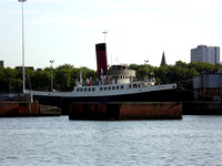 The preserved tug Calshot is moored in front of Queen Mary 2